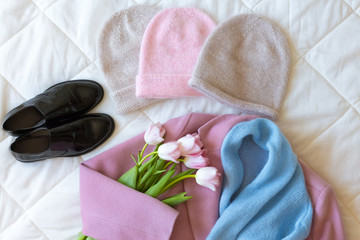 Obraz na płótnie Canvas Manually knitted hats, black patent leather shoes, pink cashmere coat, blue woollen scarf and fresh pink tulips