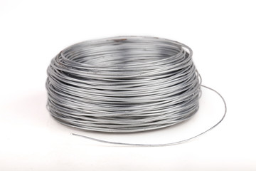 Spool of metal wire on a white surface. Isolated on white background.