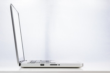 Modern laptop computer on abstract business background, side view