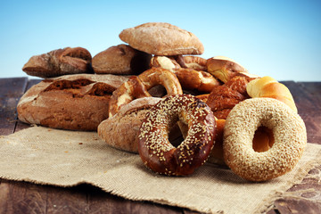 Different kinds of bread and bread rolls on board from above. Kitchen or bakery poster design.