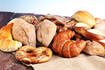 Different kinds of bread and bread rolls on board from above. Kitchen or bakery poster design.