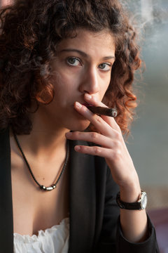 A beautiful girl with blue eyes smoking a Tuscan cigar