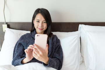 Woman using mobile phone and lying on bed