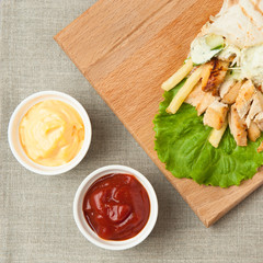 Chicken shawarma and cups with ketchup and cheese on the table