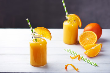 Fresh orange juice in the jar with straw on white wood table. Vertical shot