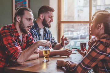 Group of Hipster Friends drinking beer and talking at the bar