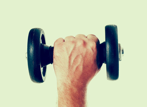 Man hand lift dumbbell on green background with retro fade out color effect