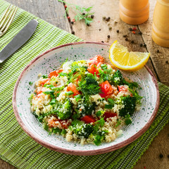 Healthy salad made of couscous, broccoli, tomato, pepper, onion and dill on a table. Traditional Moroccan food for healthy meal. Top view.