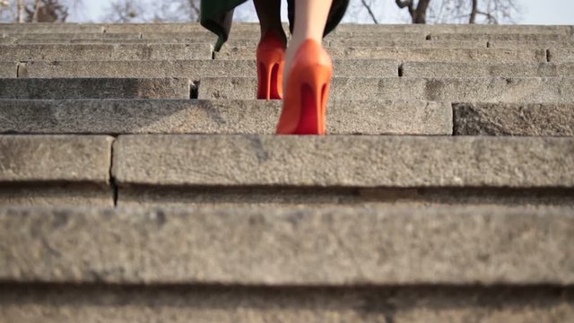 Female legs walking upstairs on stone staircase