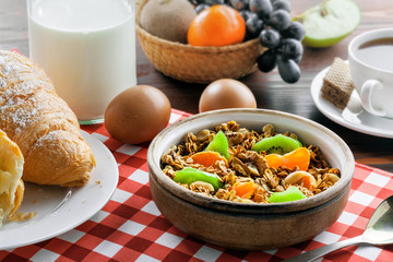 Healthy food for breakfast on a brown wooden table. Oatmeal granola with nuts, coffee, croissants, eggs, milk and fruits for delicious healthy meal.