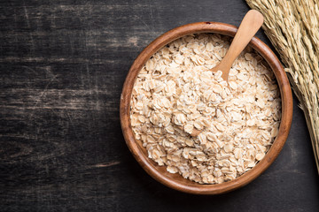 Oatmeal or oat flakes on dark wooden table
