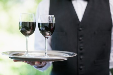 Male waiter holding tray with wine glasses