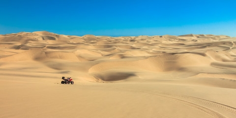 Fototapeta na wymiar Quad driving in sand desert. ATV in middle of nowhere.