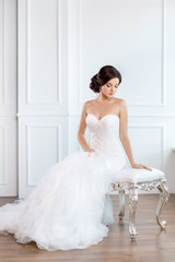 Fototapeta premium Bride in beautiful dress sitting on chair indoors