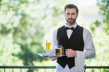 Male waiter holding tray with beer glass