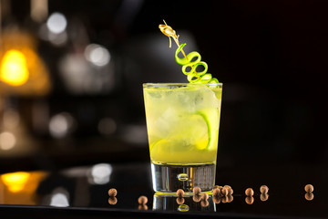 Closeup glass of fresh homemade lemonade with lemon and cucumber at dark bar counter background.