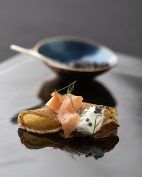 Close up of mini crepe with salmon, dill, cream and caviar.