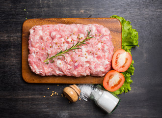 Minced pork uncooked with cutting board on wood background, top view