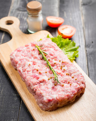 Minced pork uncooked with cutting board on wood background