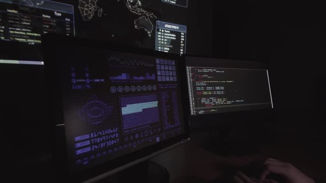 Hacker typing computer code on keyboard in dark room