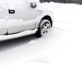 White truck parked in driveway covered with deep snow during winter storm