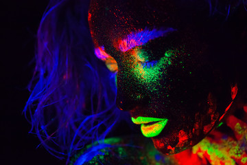 Beautiful extraterrestrial model woman with blue heair and green lips in neon light. It is portrait of beautiful model with fluorescent make-up, Art design of female posing in UV with colorful make up