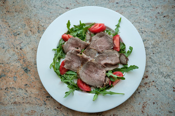Healthy food. Salad from arugula, tomatoes and roast beef.