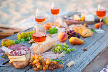 Picnic on the beach at sunset in boho style, food and drink concept