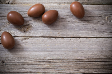 Chocolate eggs on old wooden background