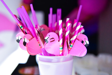 Glass containing many pink straws with a flamingo attached to them
