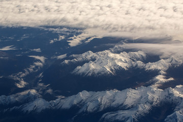 Idyllic snowy mountain peaks under clouds from plane