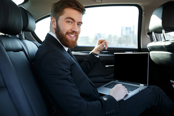 Fototapeta na wymiar Side view of smiling business man with laptop