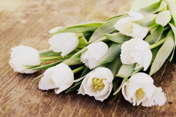 Fototapeta na wymiar bouquet de tulipes blanches sur fond planche en bois,arrière plan rustique