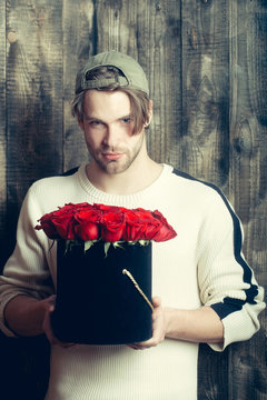 bearded man holds red rose flowers in box