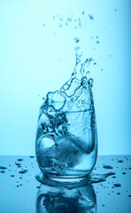 Ice cubes splashing into glass of water