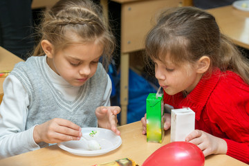 Two children are drinking juice and eating cake at a party at school