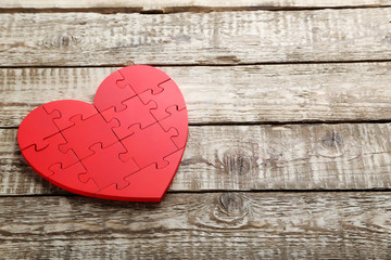 Red puzzle heart on grey wooden background