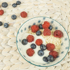 Frisches Müsli mit Himbeeren und Blaubeeren dazu Haferflocken und Jogurt, quadratisch