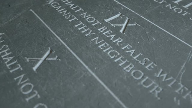 A slow close up pan across a stone tablet with the first five of the ten commandments inscribed onto them