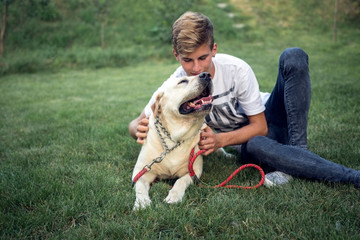 Adolescent male with labrador spend time on the grass in the yard