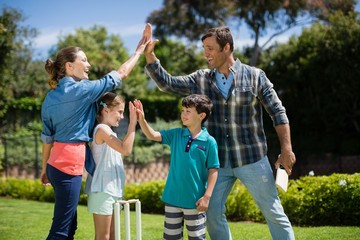 Family giving high five to each other while playing cricket