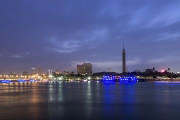 Cairo city center at twilight, the Kasr El Nile Bridge and the island of Zamalek with its colorful boats on the Nile river.