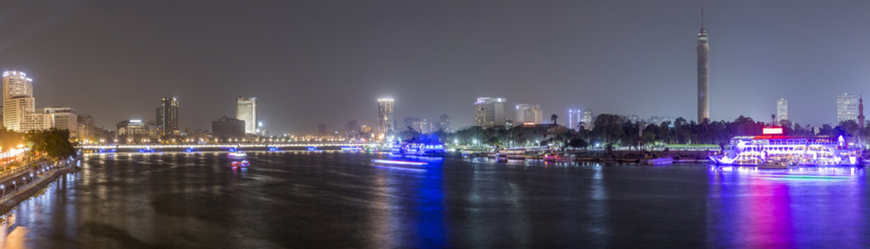 Panoramic view of Cairo city center at night, the Kasr El Nile Bridge and the island of Zamalek with its colorful boats on the Nile river.