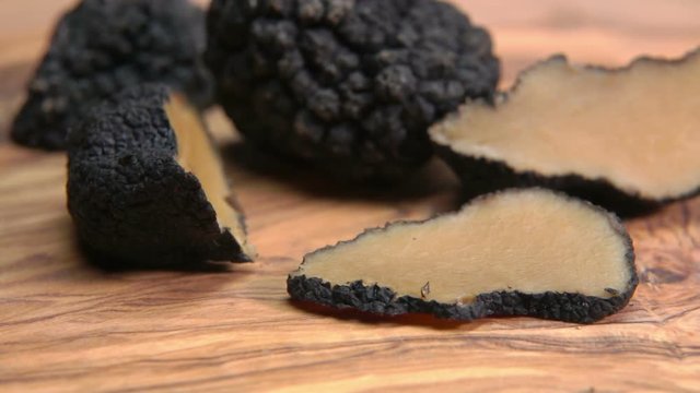 slices and tubers of black truffle lying on a wooden board