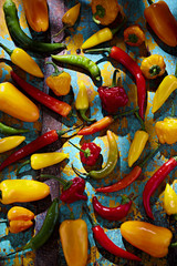 Green, red, yellow and orange peppers on blue background