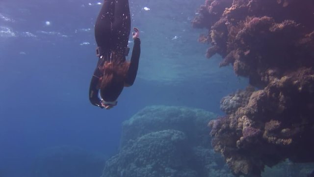 Underwater model free diver swims in clean transparent blue water in Red Sea. Filming a movie.