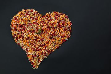 Heart shaped mix of red and yellow corn grains and wheat grains on market stall