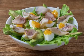 Salad of squid with egg and fresh vegetables on a wooden background