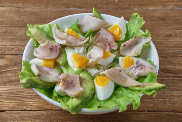 Salad of squid with egg and fresh vegetables on a wooden background