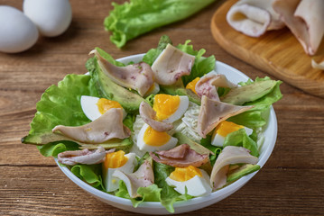 Salad of squid with egg and fresh vegetables on a wooden background